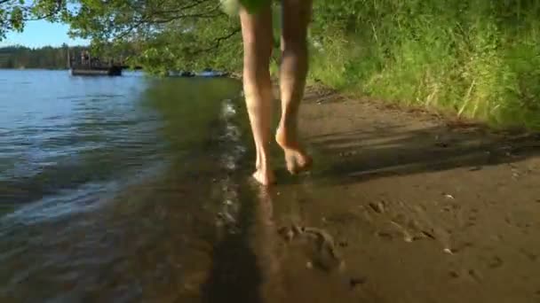 Une jeune femme marche sur l'eau le long de la rive d'un lac forestier — Video