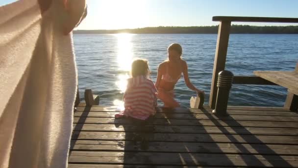 A man wraps a towel around his wife and daughter after swimming in the lak — Stockvideo