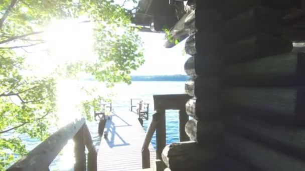 Una mujer corriendo por las escaleras desde la sauna hasta el muelle de madera para saltar al lago — Vídeo de stock