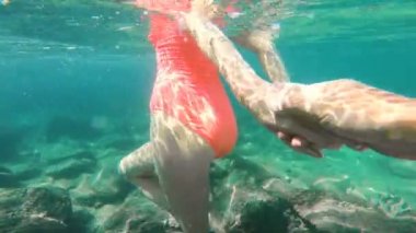 Beni takip edin. Genç bir kadın erkek arkadaşını turkuazın içine sokuyor. Suları, sualtı filmlerini görüyor..