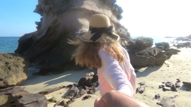 Sígueme. Feliz joven pelirroja en el hombre líder cogido de la mano en la playa tropical con acantilados vacaciones viaje de verano . — Vídeo de stock