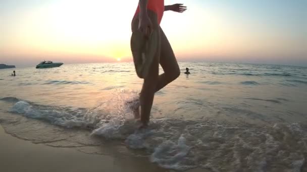 Jovem mulher esbelta andando na praia do oceano ao pôr do sol — Vídeo de Stock