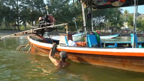 Fischer säubert frühmorgens in Thailand das Heck seines alten Bootes — Stockvideo