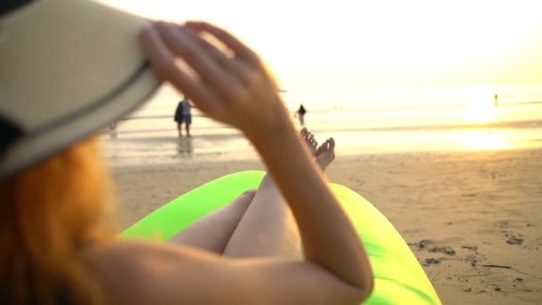 Μια νεαρή γυναίκα με ψάθινο καπέλο απολαμβάνοντας την ηρεμία και την ησυχία στο ηλιοβασίλεμα στην παραλία — Αρχείο Βίντεο
