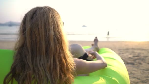 Молода жінка в солом'яному капелюсі насолоджується спокоєм і приватністю на заході сонця на пляжі — стокове відео
