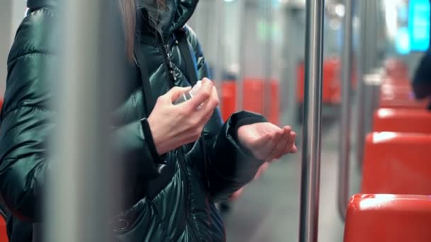 Una mujer joven usa líquido desinfectante de manos en un vagón subterráneo — Vídeo de stock