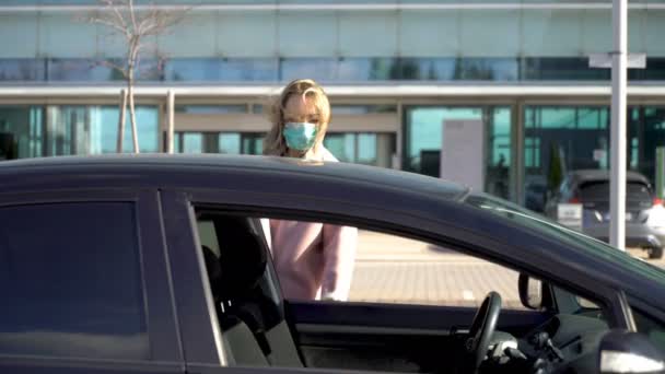 Молодая женщина в защитной стерильной маске для лица в машине , — стоковое видео