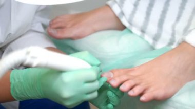 Pedikür uzmanı güzellik salonunda estetik donanım pedikürü yapıyor..