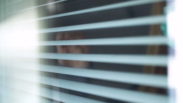 Sad young woman wearing medical protection mask looking out the window — Stock Video