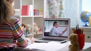 Orta yaşlı erkek mesafe öğretmeni bilgisayardaki konferansta öğrenciyle iletişim kuruyor.