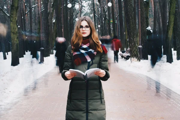 Portrait d'une belle jeune fille avec des lunettes, lèvres rouges, dans une veste, une écharpe nouée autour de son cou livre de lecture — Photo