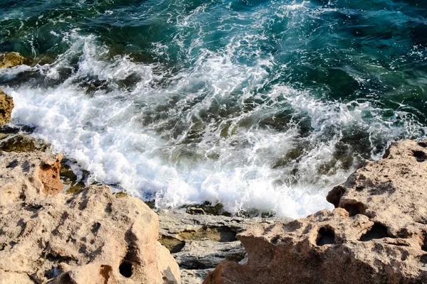 Havsvatten vågor slå klippor och bildar ett skum — Stockfoto