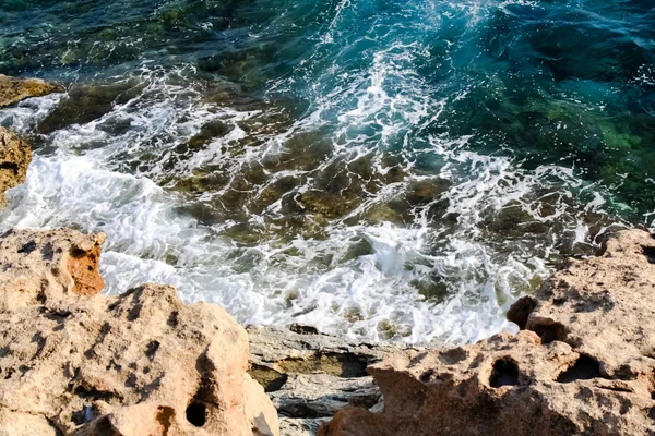 Havsvatten vågor slå klippor och bildar ett skum — Stockfoto