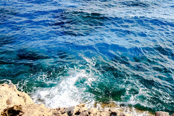 Las olas de agua de mar golpean las rocas y forman una espuma —  Fotos de Stock
