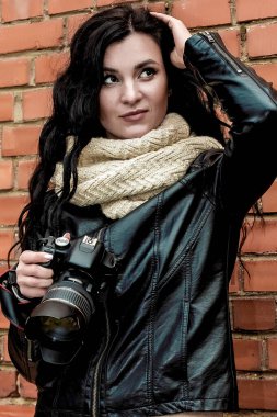 Güzel bir esmer kız fotoğrafçının portresi. Uzun kıvırcık saçlı, ılık sonbahar kıyafetleri içinde.