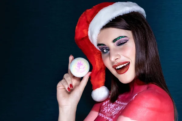 Una ragazza bruna in un cappello di Babbo Natale di notte su sfondo blu — Foto Stock