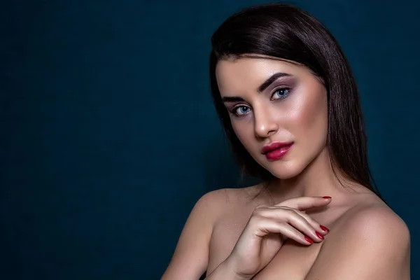 Esmer kız, uzun ve parlak uzun saçlı ve mavi arka planda mükemmel makyajlı..