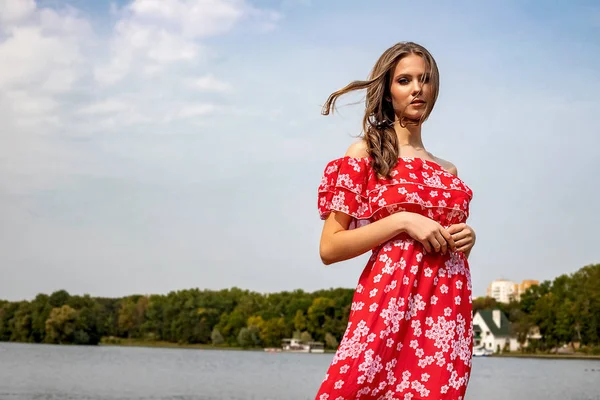 Портрет красивой молодой каштановой девушки с длинными волосами в красном платье на озере . — стоковое фото