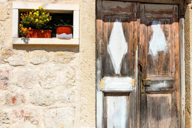 Taş bir duvarı ve güzel bir kapısı olan otantik bir ev ve girişte çiçekli saksılar, minimal stil, parlak renkler, arka plan. Karadağ