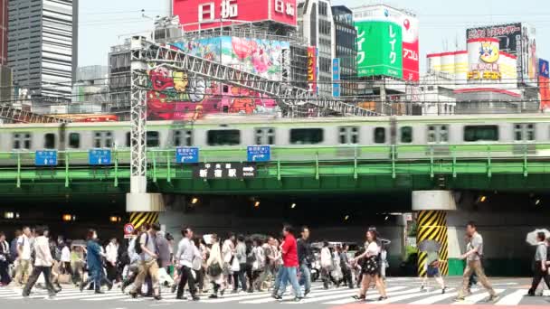 Tokio - Menschen auf einem Fußgängerüberweg mit bunten Werbetafeln und vorbeifahrenden Zügen. 4K — Stockvideo