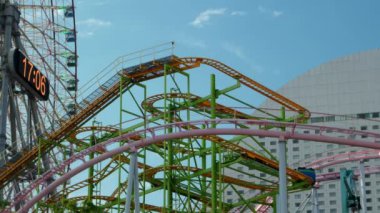 Yokohama - Haziran 2016: Yokohama Cosmoworld 'de dönme dolap ve hız treniyle lunapark eğlenceleri. 4K çözünürlüğü