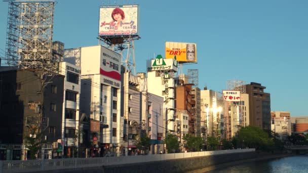 Fukuoka - Juli 2016: Utsikt över flodbanken med byggnader och skyltar i kvällsljus. 4K-upplösningshastighet. — Stockvideo