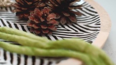 Modern Noel kompozisyonu. Siyah beyaz ringa balığı desenli tabak, saman yıldızı, kozalak ve kalın yeşil yün iplik. 4K çözünürlük yakın çekim, taşımacılık çekimi.