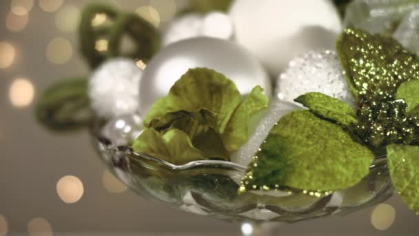 Composizione natalizia in toni verdi e bianchi con fiore di Poinsettia e bagattelle in piatto di caramelle di vetro. 4K risoluzione tiro autotrasporto. Profondità di campo ridotta . — Video Stock