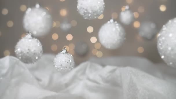 Boules de Noël tournant au-dessus de la neige blanche avec des lumières déconcentrées en arrière-plan. Résolution 4K dolly shot. Profondeur de champ faible . — Video