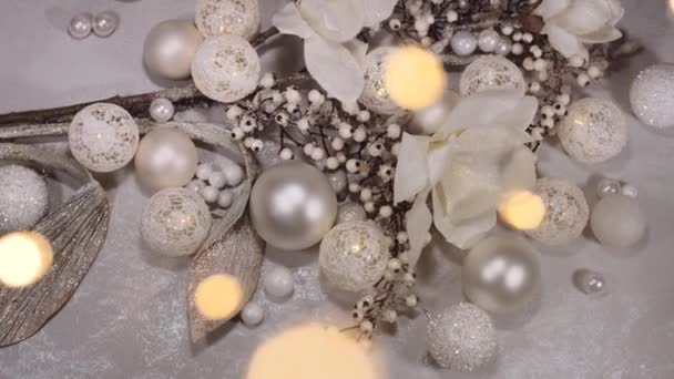 Composition de Noël composée de boules blanches, de fleurs et de lumières déconcentrées au premier plan et en arrière-plan. Résolution 4K tir de camion. Vue du dessus .