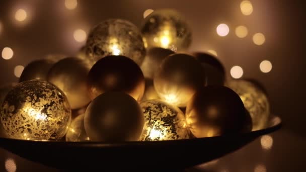 Χριστουγεννιάτικα μπιχλιμπίδια σε μεταλλικό πιάτο που λάμπουν στο σκοτάδι με φώτα στο παρασκήνιο. Σφηνάκι με ανάλυση 4K. — Αρχείο Βίντεο