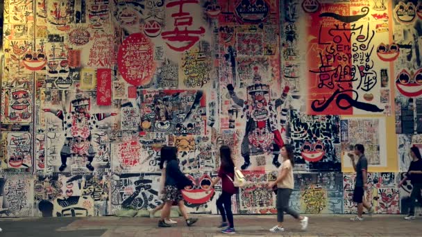 Hong Kong Orang-orang berjalan di depan dinding dengan gambar berwarna-warni. Gerakan lambat. — Stok Video