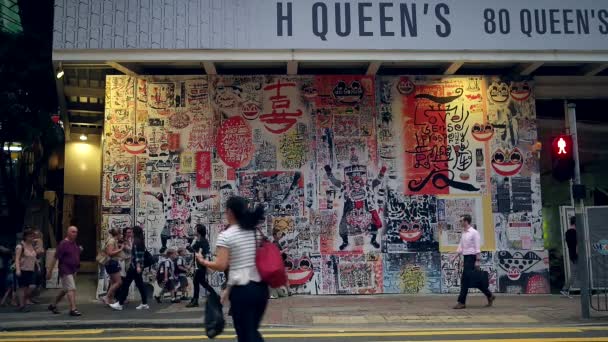 香港-人々はカラフルな図面で壁の前を歩く。スローモーション. — ストック動画
