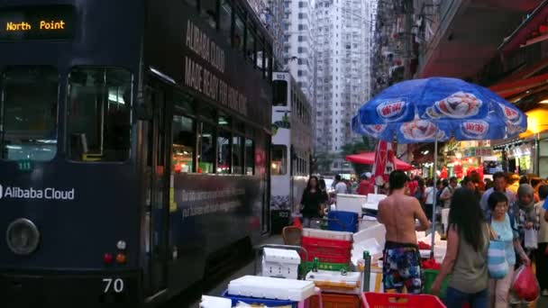 HONG KONG - Wieczorny widok mokrego rynku z ludźmi i dwupiętrowych tramwajów przejeżdżających. Rozdzielczość 4K. — Wideo stockowe