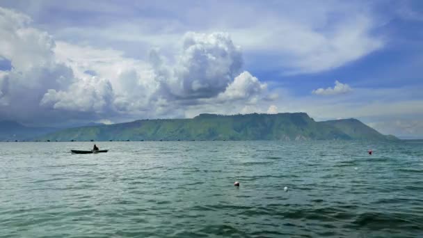 Vista do Lago Toba com pescador em pequeno barco e nuvens dinâmicas. Resolução 4K . — Vídeo de Stock