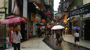 Macao - yağmurlu günlerde Macao Tarih Merkezi 'nde şemsiyeli insanlar yürüyor. 4K çözünürlüğü