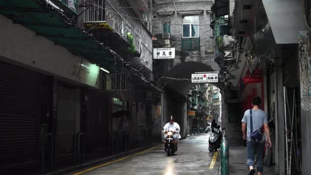 Макао - Люди и движение по маленькой очаровательной улице с арочным тоннелем в дождливый день. Разрешение 4K — стоковое видео