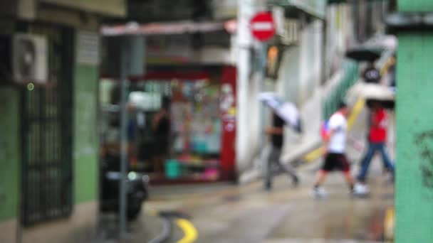 Macao - Menschen mit Regenschirmen gehen durch eine kleine charmante Straße. Defokussierter Blick. 4K-Auflösung. — Stockvideo