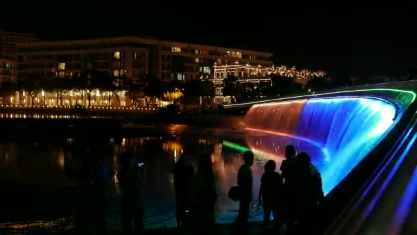 Ho Chi Minh City - Kleurrijke waterval 's nachts met silhouetten van mensen, Starlight brug. 4K-resolutieverjaring. — Stockvideo