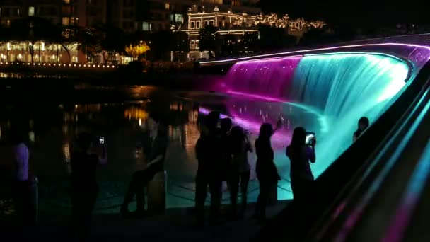 Ho Chi Minh City - Kleurrijke waterval 's nachts met silhouetten van mensen, Starlight brug. 4K-resolutieverjaring. — Stockvideo