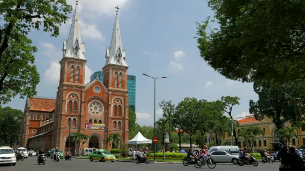 Ho Chi Minh City - Street view met verkeer en mensen in de voorkant van de kathedraal. 4K-resolutie. — Stockvideo