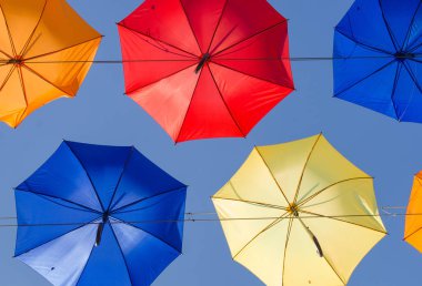 Mavi gökyüzünde birçok çok renkli şemsiyeler