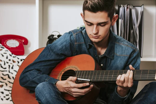 Joven teléfono móvil y guitarra — Foto de Stock