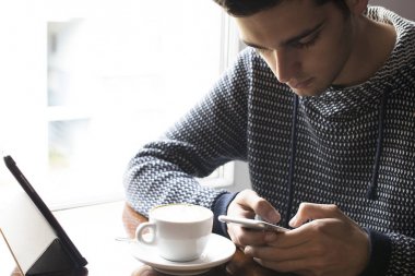 adam cep telefonu ile kafeteryada 