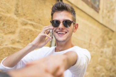 genç adam telefonda konuşurken onun elini tutarak