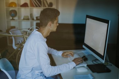 Evde bilgisayarı olan genç bir adam.