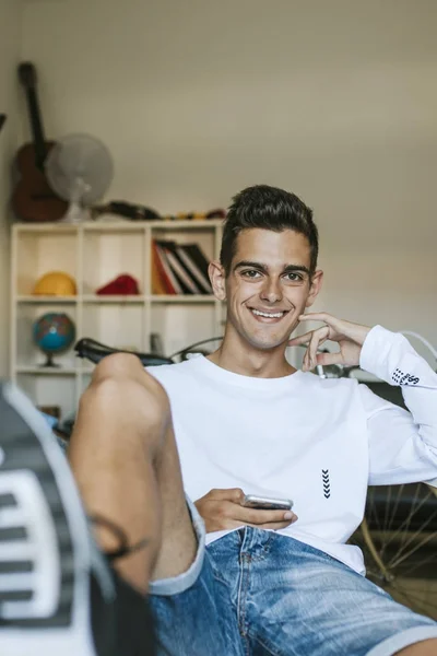 young man smiling with the mobile phone at home