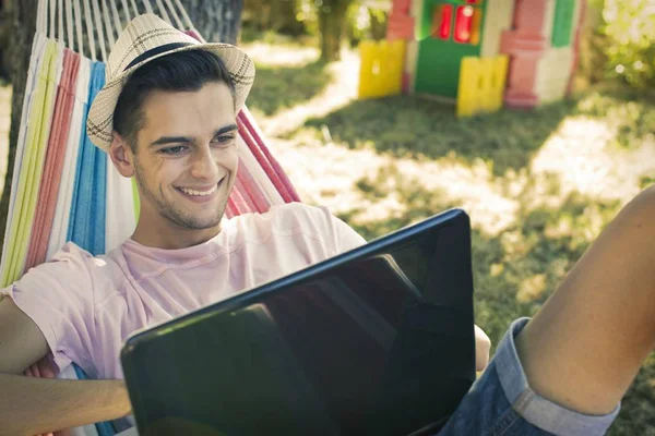 年轻的人或十几岁的笔记本电脑在日落夏天的吊床 — 图库照片