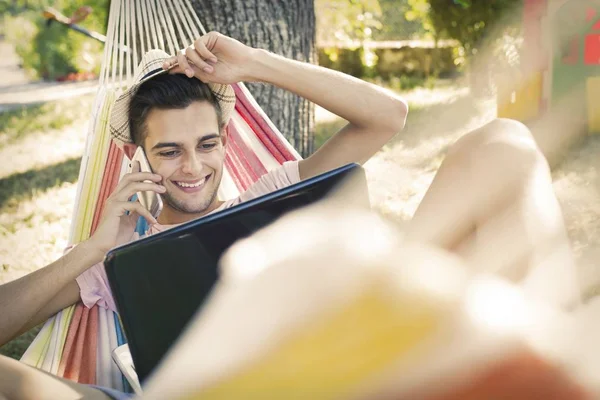 年轻的人或十几岁的笔记本电脑在日落夏天的吊床 — 图库照片