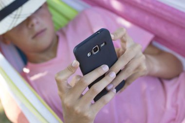 child in hammock with mobile phone clipart